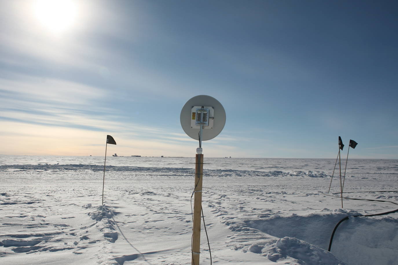 The antenna provides network connections with the station. At the horizon you can see, very small, the South Pole Telescope and the station.