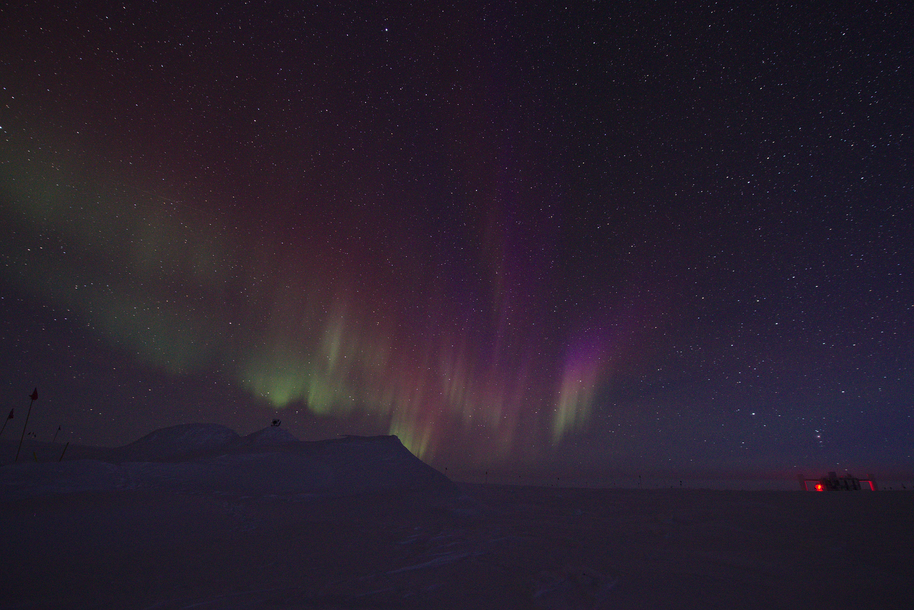 Green, orange, red, and pink auroras. Because of the very clean air above south pole we rarely see such beautiful colours. The IceCube Neutrino Detectro Laboratory is on the right hand-side