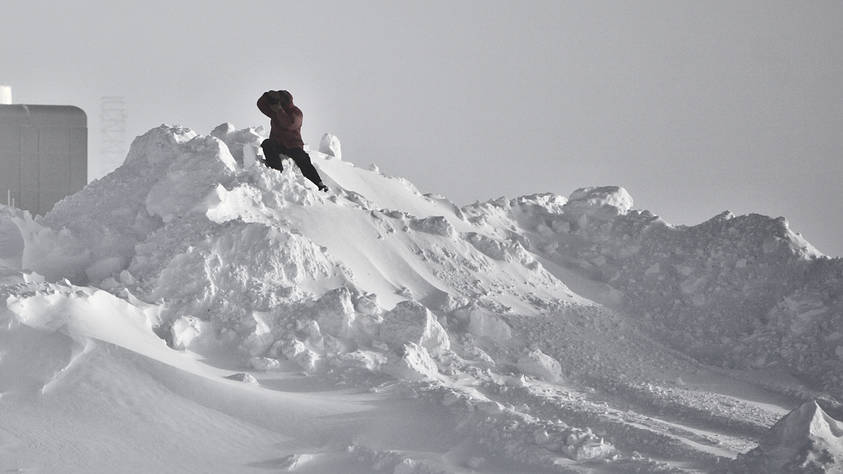 A photographer climbing a snow hill to get a good angle of the arriving aircraft