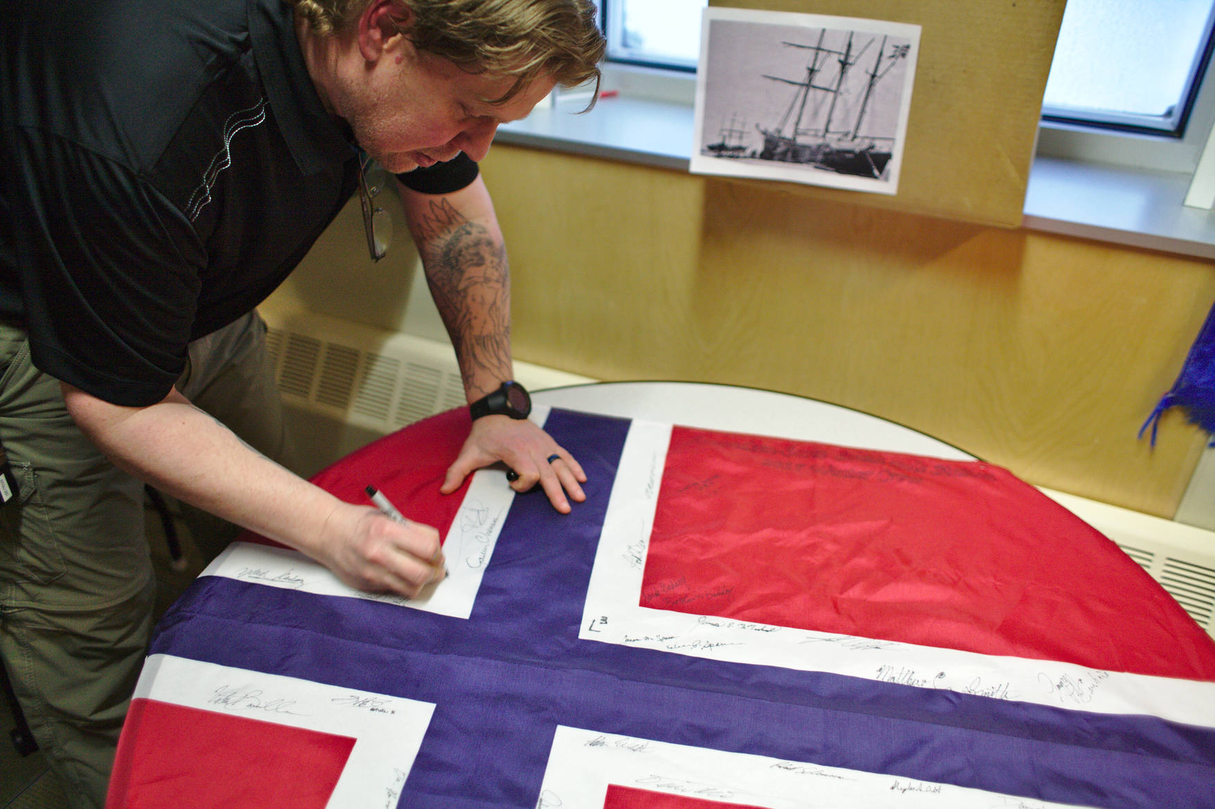 The Norwegian flag was signed by the station population. It will be taken to the polar exploration ship <em>Fram</em>, in commemoration of her use on Amundsen's 1910-12 south pole expedition (picture in the background).